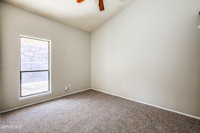 carpeted spare room featuring vaulted ceiling, a ceiling fan, baseboards, and a textured ceiling