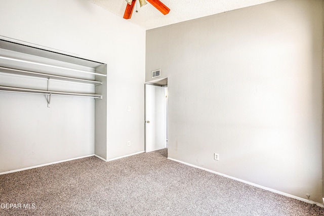 unfurnished bedroom with carpet, baseboards, visible vents, ceiling fan, and a towering ceiling