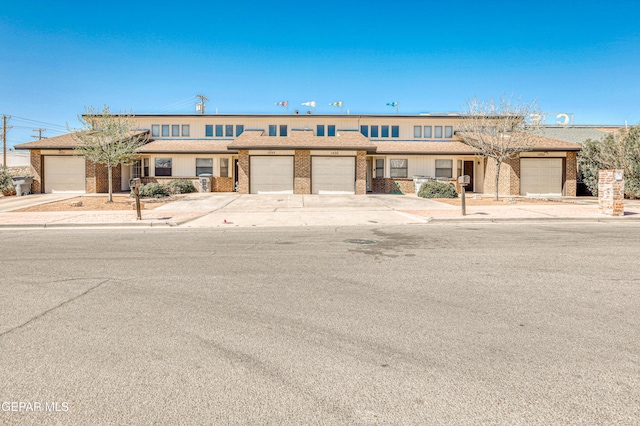 multi unit property with a garage, brick siding, and concrete driveway