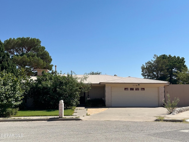 single story home with brick siding, driveway, metal roof, and a garage