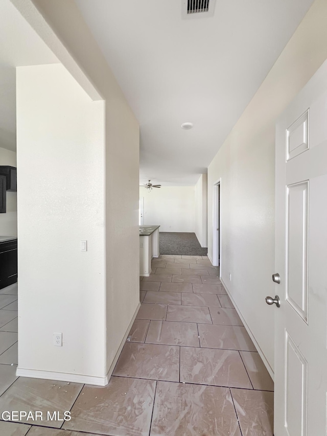 hallway featuring tile patterned flooring and baseboards