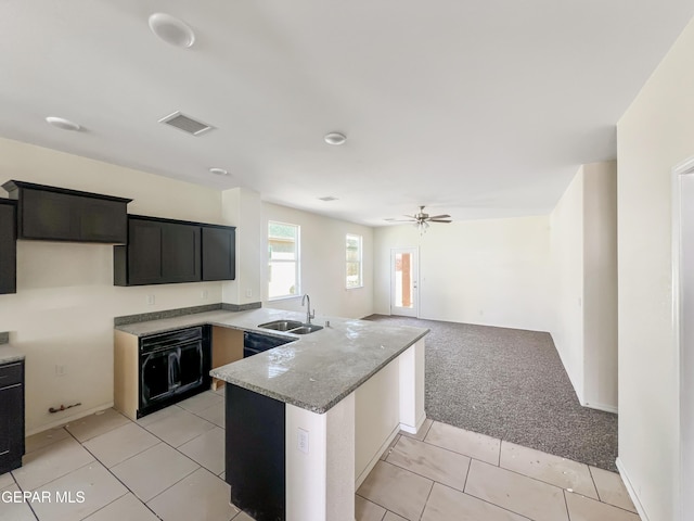 kitchen featuring light colored carpet, a peninsula, a sink, visible vents, and light stone countertops