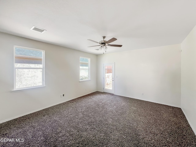 spare room featuring carpet floors, visible vents, and a ceiling fan