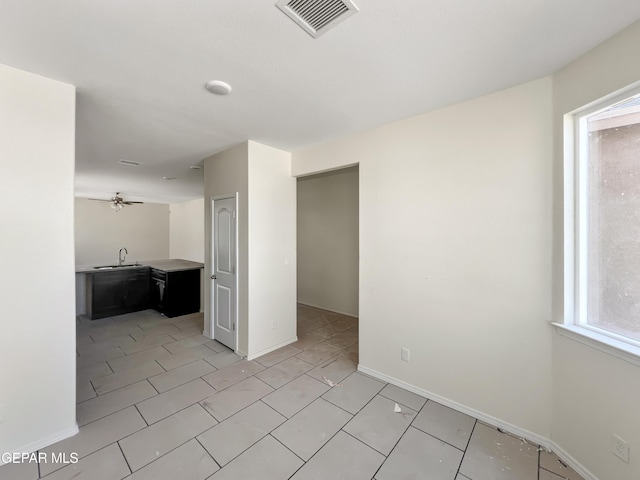 spare room featuring plenty of natural light, a sink, visible vents, and baseboards