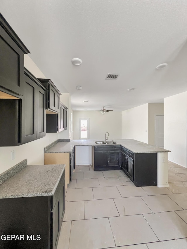 kitchen featuring ceiling fan, light tile patterned flooring, dark cabinets, a sink, and visible vents