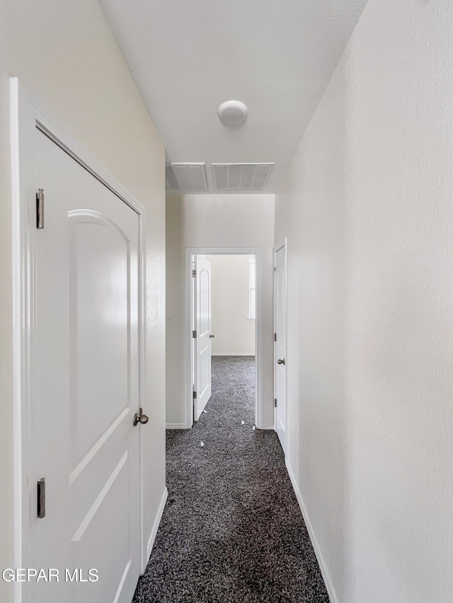 hall with carpet floors, visible vents, and baseboards