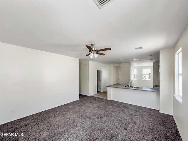 unfurnished living room featuring light carpet, a sink, visible vents, and a ceiling fan