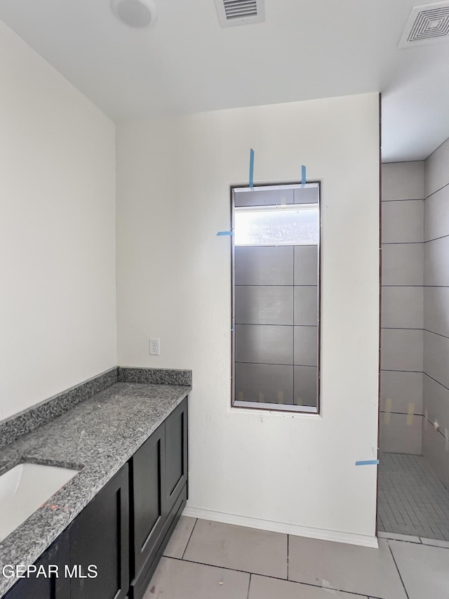 bathroom with vanity, tile patterned flooring, a tile shower, and visible vents