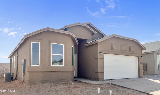 view of front of property featuring cooling unit, concrete driveway, an attached garage, and stucco siding