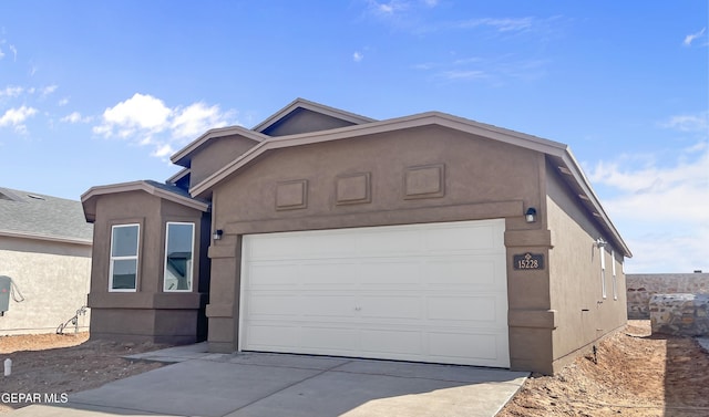 view of front of house featuring driveway, an attached garage, and stucco siding