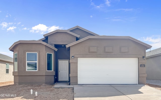 single story home featuring a garage, concrete driveway, and stucco siding