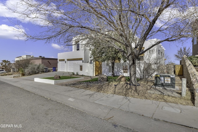 view of front of property featuring concrete driveway, fence, and stucco siding