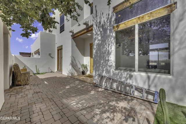 exterior space with a patio, fence, and stucco siding