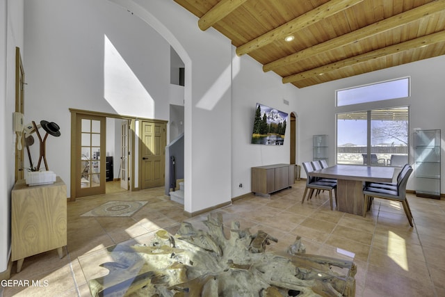 living room with arched walkways, wooden ceiling, a towering ceiling, and beam ceiling