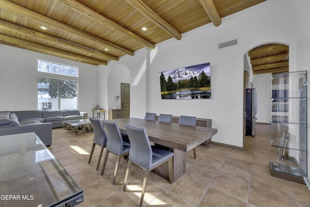 dining area featuring arched walkways, light tile patterned floors, wooden ceiling, a high ceiling, and beam ceiling