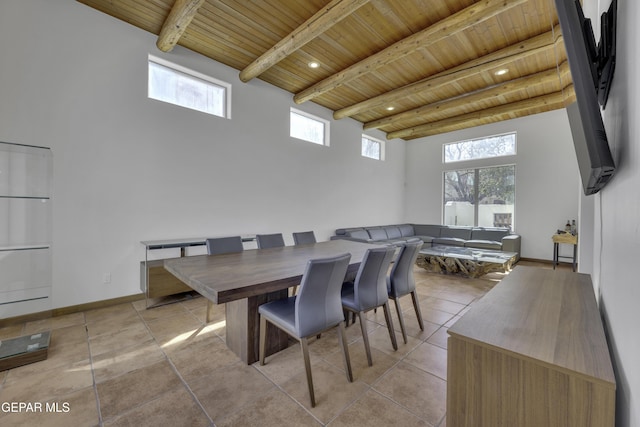 dining space with wooden ceiling, light tile patterned flooring, beamed ceiling, and a high ceiling