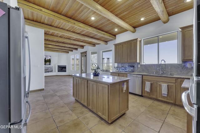 kitchen with a center island, light tile patterned floors, tasteful backsplash, appliances with stainless steel finishes, and a sink