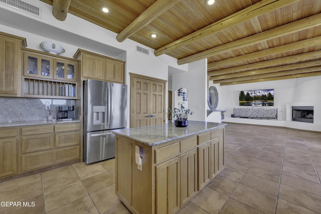 kitchen with light stone counters, light tile patterned floors, visible vents, open floor plan, and stainless steel fridge