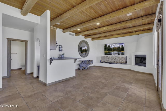 interior space with wood ceiling, visible vents, a fireplace with raised hearth, and beamed ceiling