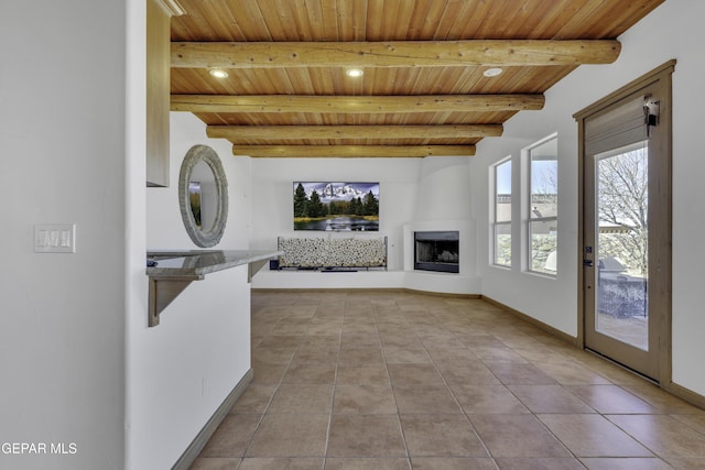 unfurnished living room with a fireplace with raised hearth, wooden ceiling, tile patterned flooring, and beam ceiling