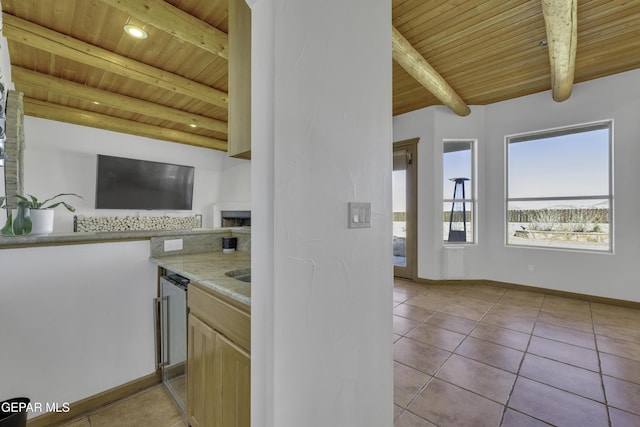 kitchen featuring wooden ceiling, baseboards, beam ceiling, and light tile patterned floors