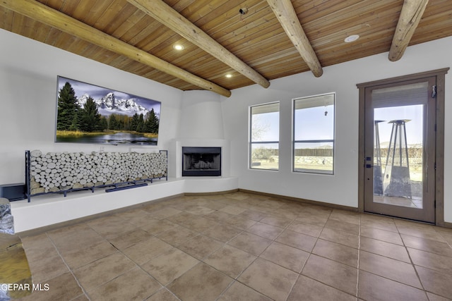 unfurnished living room with wood ceiling, a large fireplace, tile patterned flooring, beamed ceiling, and baseboards