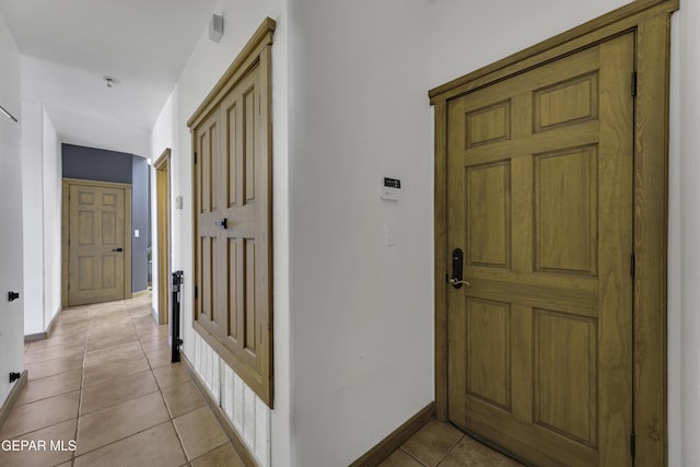 hallway with light tile patterned floors and baseboards