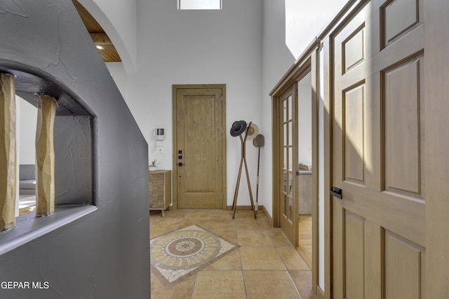 entryway with light tile patterned floors and a high ceiling