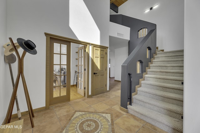 interior space featuring tile patterned flooring, a high ceiling, visible vents, and french doors