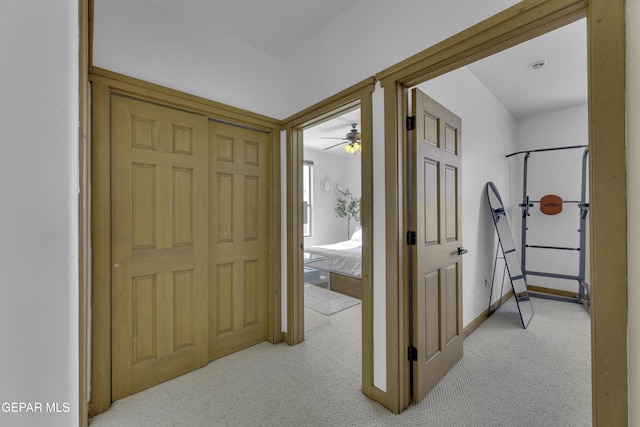 hall featuring baseboards and light colored carpet