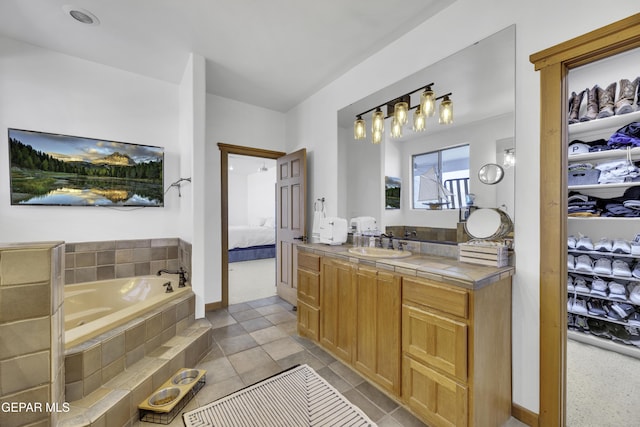 bathroom featuring a garden tub, a spacious closet, vanity, and ensuite bathroom