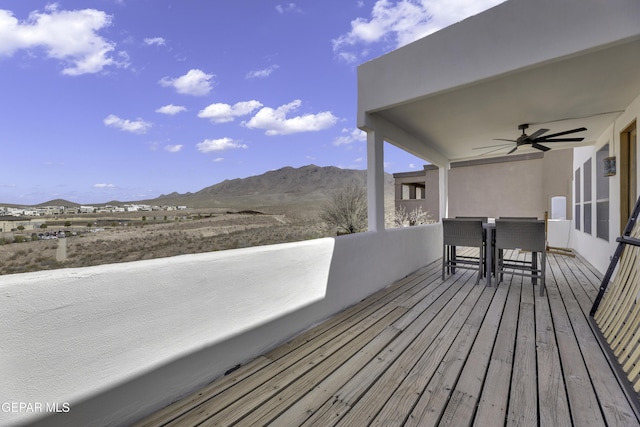 deck with a mountain view, outdoor dining area, and a ceiling fan