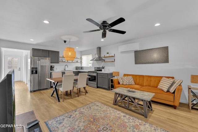 living area featuring recessed lighting, light wood-style flooring, an AC wall unit, and ceiling fan