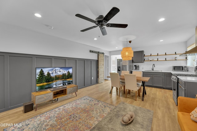 dining space featuring a barn door, light wood-style flooring, and recessed lighting