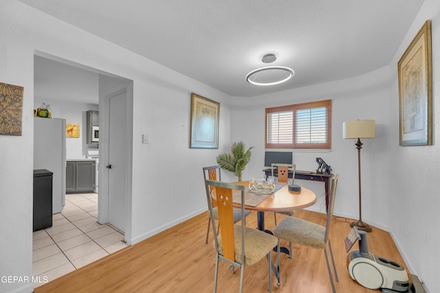 dining space featuring baseboards and light wood finished floors