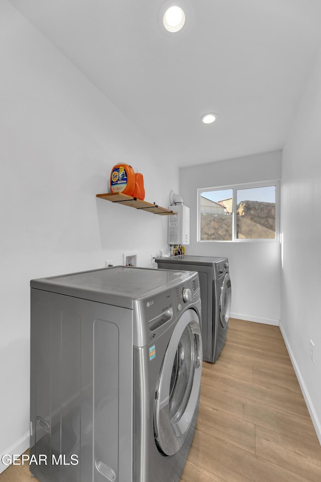 clothes washing area with light wood-style floors, baseboards, separate washer and dryer, and laundry area