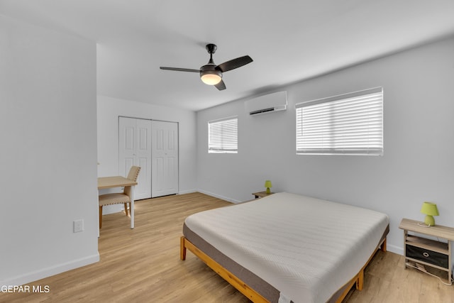 bedroom featuring a closet, a wall mounted AC, baseboards, and wood finished floors