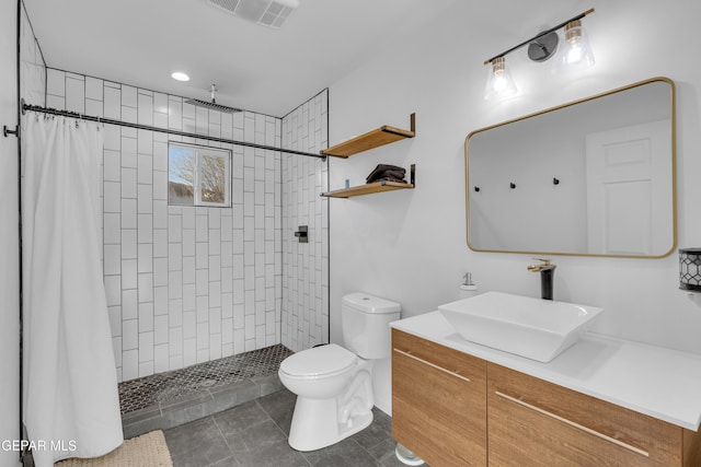 bathroom with visible vents, toilet, a tile shower, tile patterned floors, and vanity