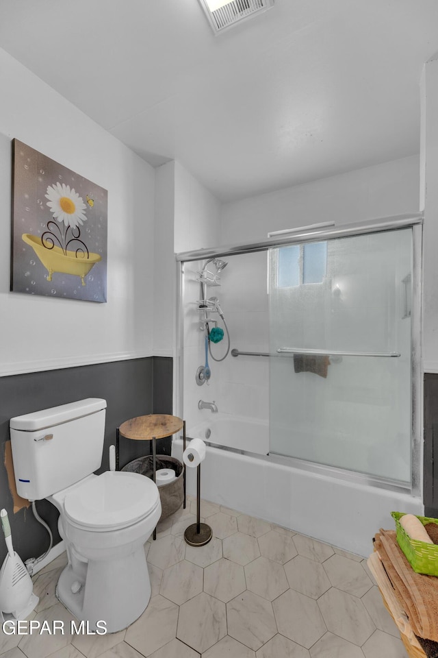 full bathroom featuring visible vents, toilet, and shower / bath combination with glass door