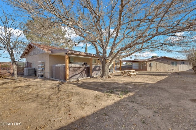 back of house featuring stucco siding and central AC