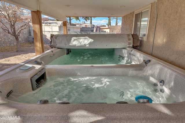 exterior details with stucco siding, a jacuzzi, and fence