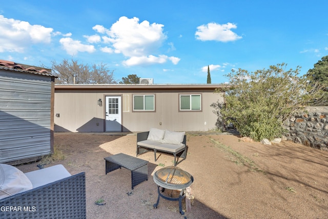 back of property with a patio and an outdoor living space with a fire pit