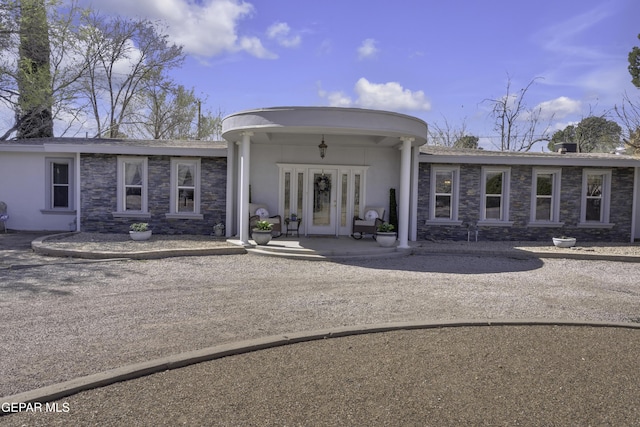 doorway to property with stone siding, stucco siding, and french doors