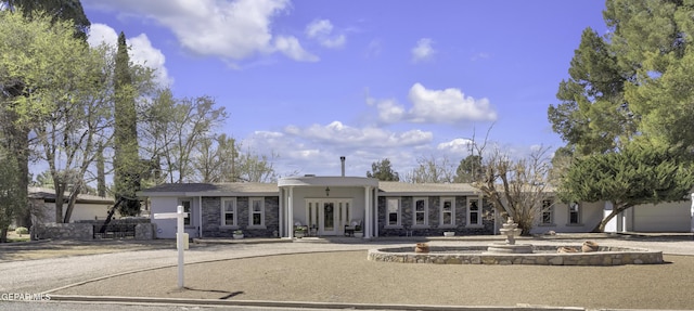 single story home featuring stone siding, french doors, and stucco siding