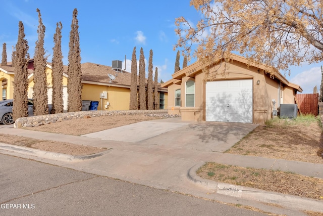 view of front of property featuring concrete driveway, central AC unit, an attached garage, and stucco siding