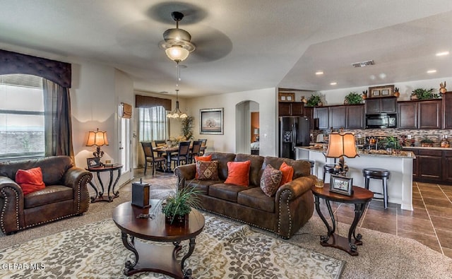 living area featuring arched walkways, tile patterned flooring, visible vents, and recessed lighting