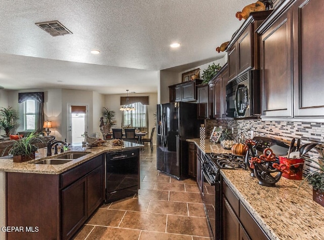 kitchen featuring visible vents, decorative backsplash, a kitchen island with sink, black appliances, and a sink