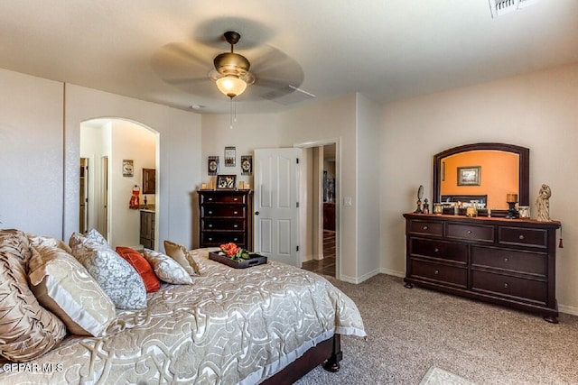 bedroom with light carpet, visible vents, arched walkways, and baseboards