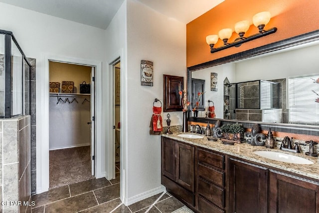 bathroom with double vanity, a shower stall, a walk in closet, and a sink