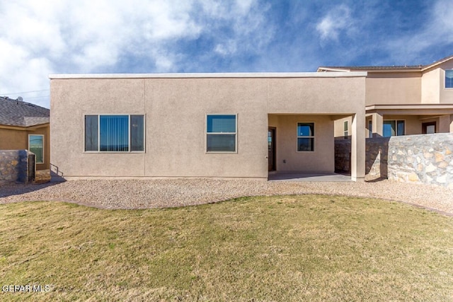 rear view of house with a patio, a lawn, and stucco siding